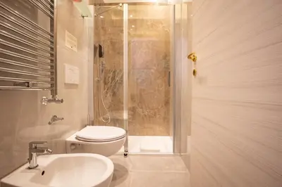 a bathroom with a shower and a toilet and a sink at Twins Royal Suite in Rome
