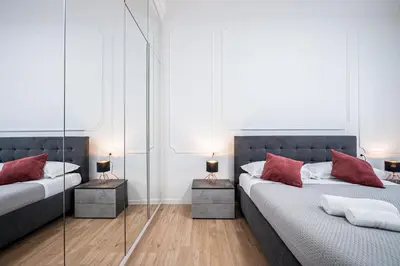 two beds in a room with mirrors and red pillows at Anna Vatican Loft - Relax al centro di Roma! in Rome
