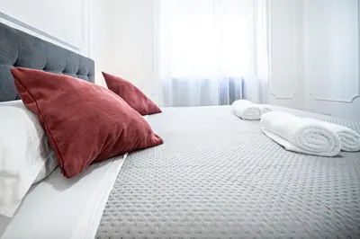 a bed with red pillows and white towels on it at Anna Vatican Loft - Relax al centro di Roma! in Rome