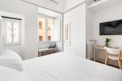 a white bedroom with a white bed and a desk at Iflat New Spacious & Classy Apartment in Monti in Rome