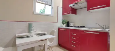 a kitchen with red cabinets and a sink at Roma Brancaleone Loft, Metro C in Rome