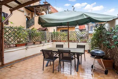 a table and chairs with an umbrella on a patio at L'Arte Dei Sogni Apartment With Terrace- Trastevere District in Rome