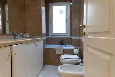 a bathroom with a toilet and a sink and a window at Sistina 138 Luxury Home in Rome