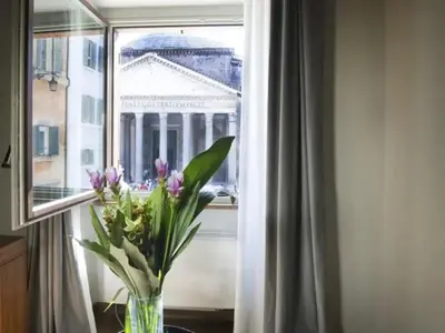 a vase of flowers sitting on a table in front of a window at pantheon suite 11 in Rome