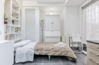 a white bedroom with a bed and a kitchen at Battistini Sweet House in Rome