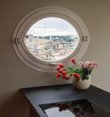 a round window with a vase of flowers on a table at Terrazze di Venere in Rome