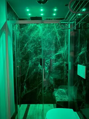 a glass shower in a bathroom with green lights at Heart Of Rome Luxe Suite in Rome