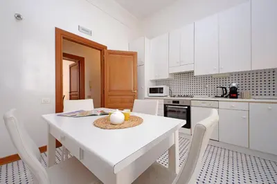 a white kitchen with a white table and chairs at Luxury home in the Ghetto's heart in Rome