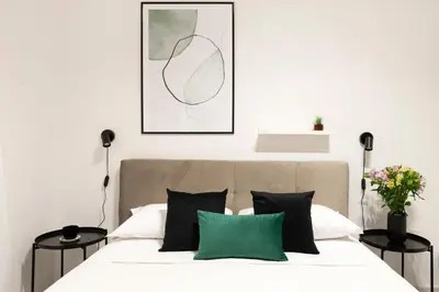 a white bedroom with a bed with green pillows at White Flat Sanniti in Rome