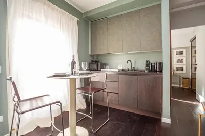 a kitchen with wooden cabinets and a table and chairs at Chic Spanish Steps Retreat in Rome