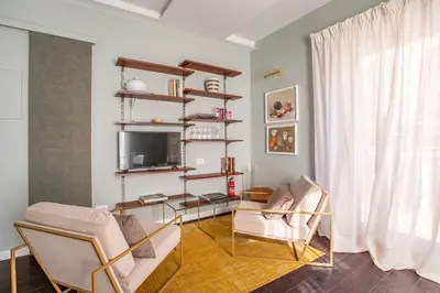 a living room with two chairs and a television at Chic Spanish Steps Retreat in Rome