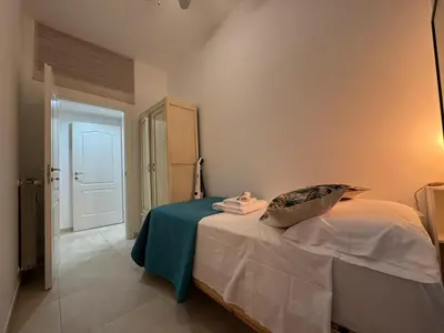 a small bedroom with a bed with a blue blanket at Warm Hideaway in Vibrant Tuscolano in Rome