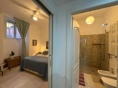 a bedroom with a bed and a bathroom with a shower at Warm Hideaway in Vibrant Tuscolano in Rome