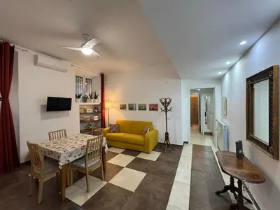 a living room with a yellow couch and a table at Warm Hideaway in Vibrant Tuscolano in Rome