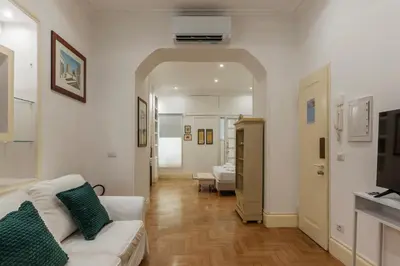 a living room with a white couch and a television at The Mirror Suite next to Spanish Steps in Rome