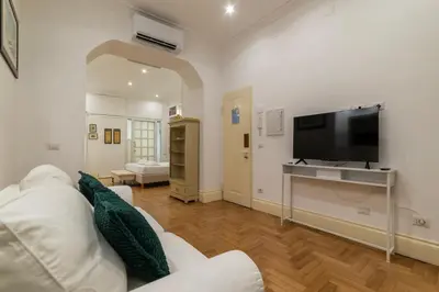 a living room with a white couch and a flat screen tv at The Mirror Suite next to Spanish Steps in Rome