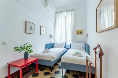a living room with two beds and a red table at Iflat Comfortable & Spacious Dolce Vita Retreat in Rome