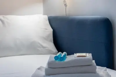 a pile of towels on a bed with a blue chair at Iflat Comfortable & Spacious Dolce Vita Retreat in Rome