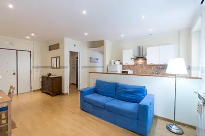 a living room with a blue couch and a kitchen at Casa Vacanze La Bomboniera in Rome