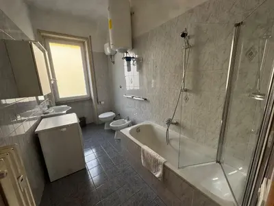 a bathroom with a tub and a shower and two toilets at Luciano Colosseo Apartment in Rome