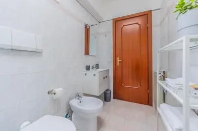 a white bathroom with a toilet and a brown door at Villa Gatta in Rome