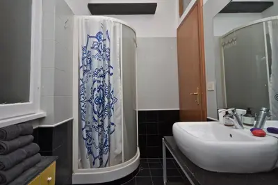 a bathroom with a sink and a blue and white shower curtain at PORTA PORTESE apartment in Rome