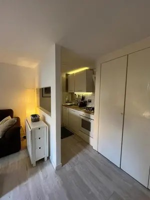a kitchen with white cabinets and a living room at LaDolcevita - Casa Milvia in Rome