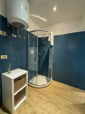 a shower in a bathroom with a blue wall at Suite San Giovanni in Rome