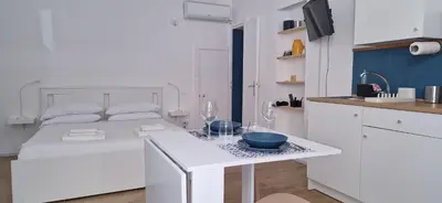 a white kitchen with a white bed and a table at Suite San Giovanni in Rome
