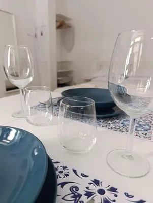 a table with four wine glasses and plates on it at Suite San Giovanni in Rome