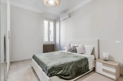 a white bedroom with a large bed and a chandelier at Biancaapartment in Rome