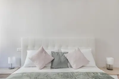 a white bedroom with a bed with four pillows at Biancaapartment in Rome
