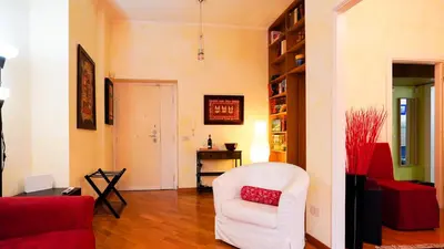 a living room with a white chair and a red couch at La Casa che Vorrei in Rome