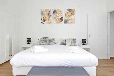 a white bedroom with a white bed and a painting at Trastevere 3 apartments by Flatinrome in Rome