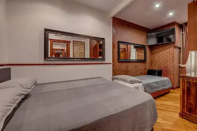 a hotel room with two beds and a mirror at Vatican Luxury Suite Bragadin in Rome