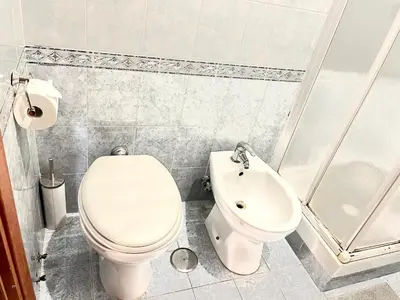 a white bathroom with a toilet and a sink at La casa di raffy in Rome