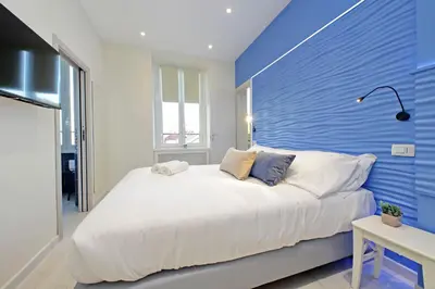 a bedroom with a white bed with a blue wall at Domus Augustea - San Giovanni Sunset Suites in Rome