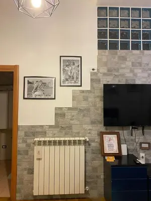 a living room with a tv and a brick wall at LaCasitaDeAU - Trastevere-Monteverde-Vaticano in Rome
