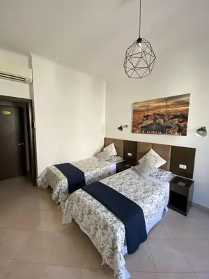 a room with three beds and a pendant light at Roomz Romestay in Rome