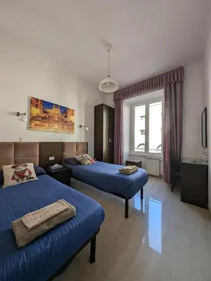 a hotel room with two beds and a window at Roomz Romestay in Rome
