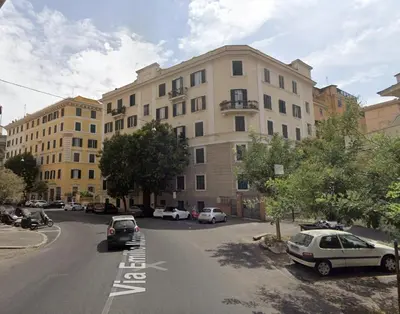 a large building with cars parked in a parking lot at Cunabu Morosini in Rome