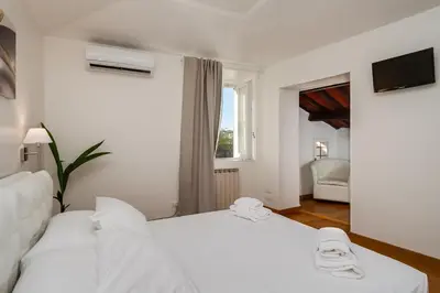a white bedroom with two beds and a window at Fabuloucity Fontana di Trevi in Rome