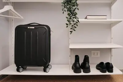 a black suitcase sitting on a shelf with shoes at Colosseo-San Giovanni, New Apartment Wi-Fi & A-C in Rome