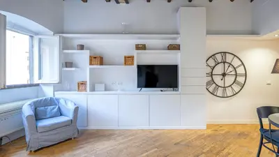 a living room with a tv and a chair and a clock at Delightful apartment-Rome Center in Rome