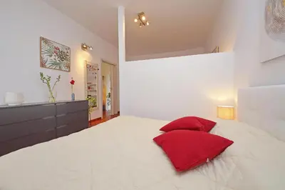 a white bedroom with red pillows on a bed at Modern Apartment near Metro Malatesta with Balcony & Wi-Fi in Rome