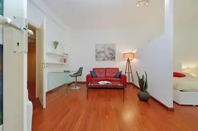 a living room with a red couch and a desk at Modern Apartment near Metro Malatesta with Balcony & Wi-Fi in Rome