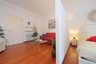 a living room with a bed and a red couch at Modern Apartment near Metro Malatesta with Balcony & Wi-Fi in Rome
