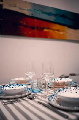 a table with plates and wine glasses and a painting at Testaccio Dream House in Rome