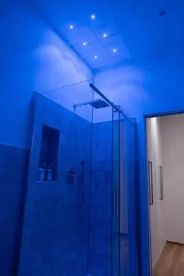 a bathroom with a glass shower with blue lighting at Testaccio Dream House in Rome