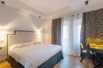 a bedroom with a bed and a desk and a window at Casa Barbieri boutique apartment Borgo Pio in Rome